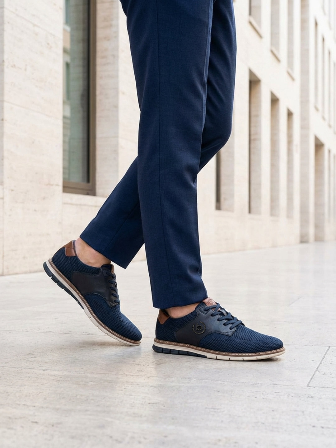 Lifestyle image of bugatti Sandman Comfort Casual Shoes in dark blue, paired with tailored blue trousers.