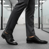 bugatti Morino I black leather derby shoes, paired with grey dress pants, in an office hallway.
