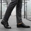 bugatti Morino I black leather derby shoes, paired with grey dress pants, in an office hallway.
