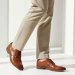 bugatti Morino I cognac brown leather formal shoes with black laces, styled with tan slacks.
