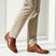 bugatti Morino I cognac brown leather formal shoes with black laces, styled with tan slacks.
