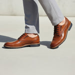 bugatti Merlo cognac leather dress shoes with black laces, paired with gray dress pants.
