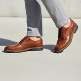 bugatti Merlo cognac leather dress shoes with black laces, paired with gray dress pants.

