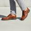 bugatti Merlo cognac leather dress shoes with black laces, paired with gray dress pants.
