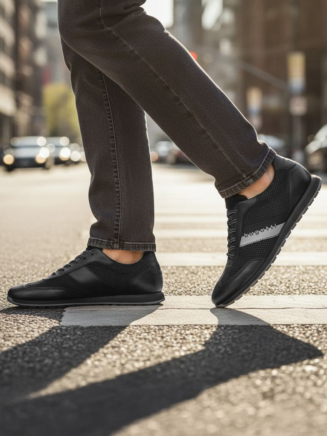 Lifestyle view of black bugatti Thorello sneakers with leather accents and a gray stripe on the side.
