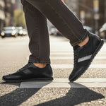 Lifestyle view of black bugatti Thorello sneakers with leather accents and a gray stripe on the side.
