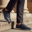 Lifestyle view of bugatti Thorello dark blue premium leather sneakers with side zip, paired with dark dress pants.
