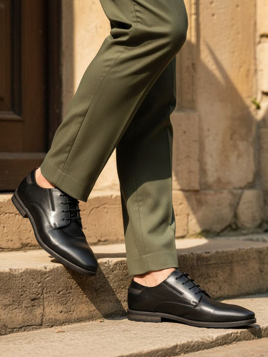 bugatti Menello black leather formal shoes with a textured finish, shown on a person with green dress pants.
