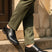 bugatti Menello black leather formal shoes with a textured finish, shown on a person with green dress pants.
