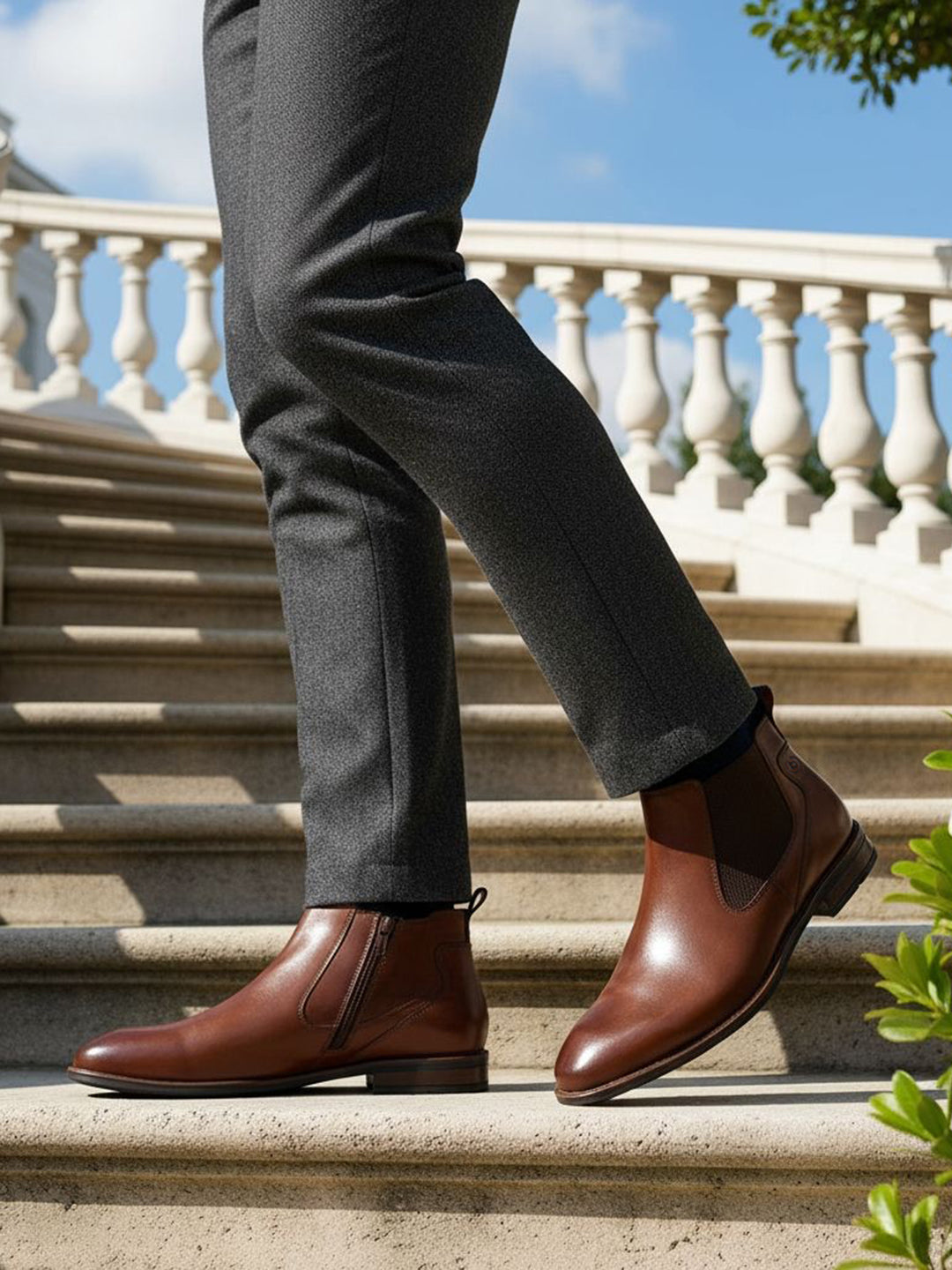 bugatti Amros Cognac Premium Leather Comfort Chelsea Boots with side zipper, worn with grey slacks on stairs.
