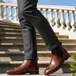 bugatti Amros Cognac Premium Leather Comfort Chelsea Boots with side zipper, worn with grey slacks on stairs.
