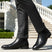 bugatti Amros black premium leather Chelsea boots, side view. Worn with dark gray trousers.
