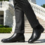bugatti Amros black premium leather Chelsea boots, side view. Worn with dark gray trousers.
