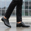 Cropped lifestyle shot of bugatti black leather formal derby shoes with textured design, paired with black dress pants.
