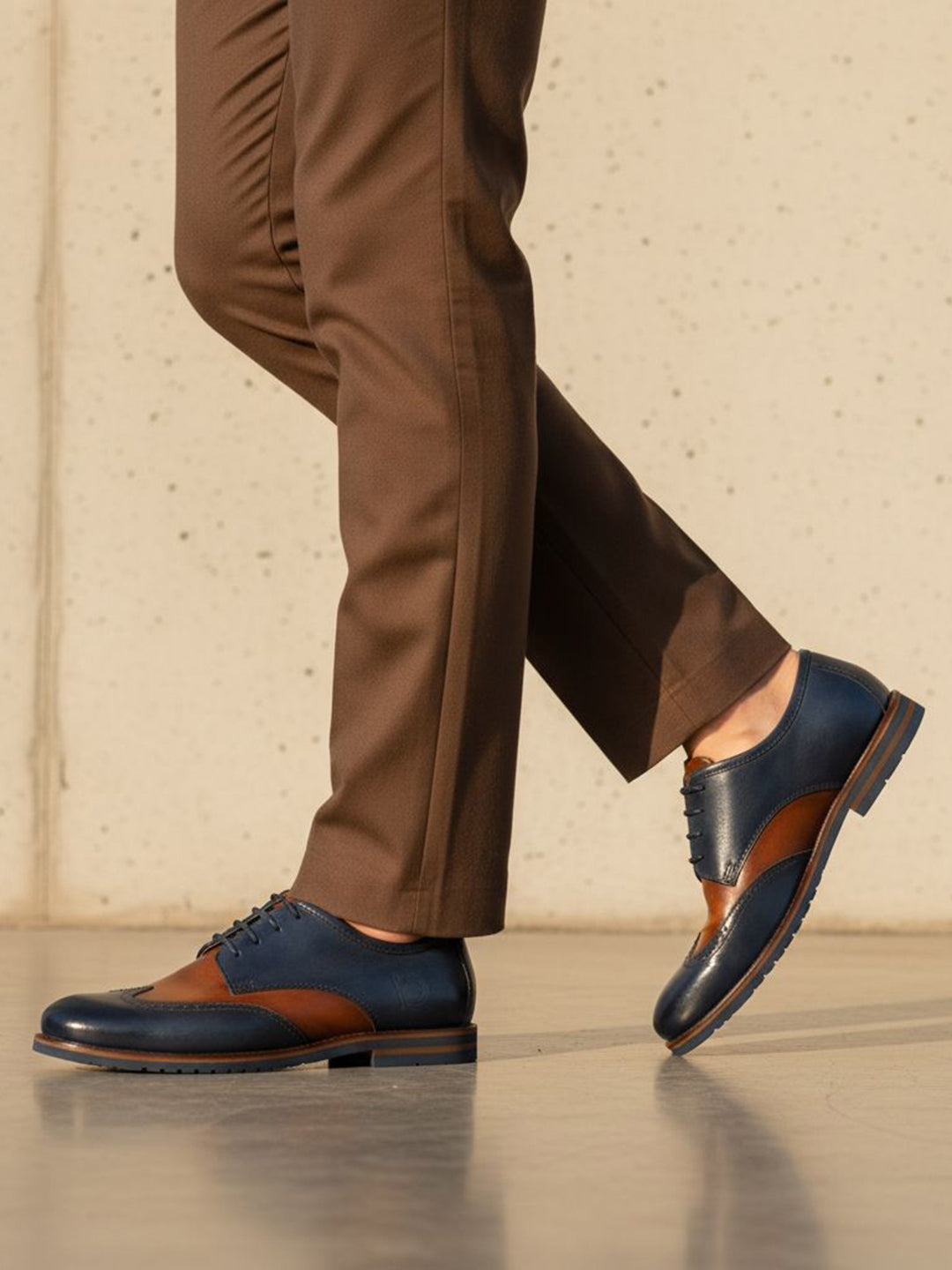 bugatti Caleo Exko dark blue leather formal shoe with brown accents, paired with brown trousers in a lifestyle shot.
