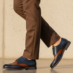 bugatti Caleo Exko dark blue leather formal shoe with brown accents, paired with brown trousers in a lifestyle shot.
