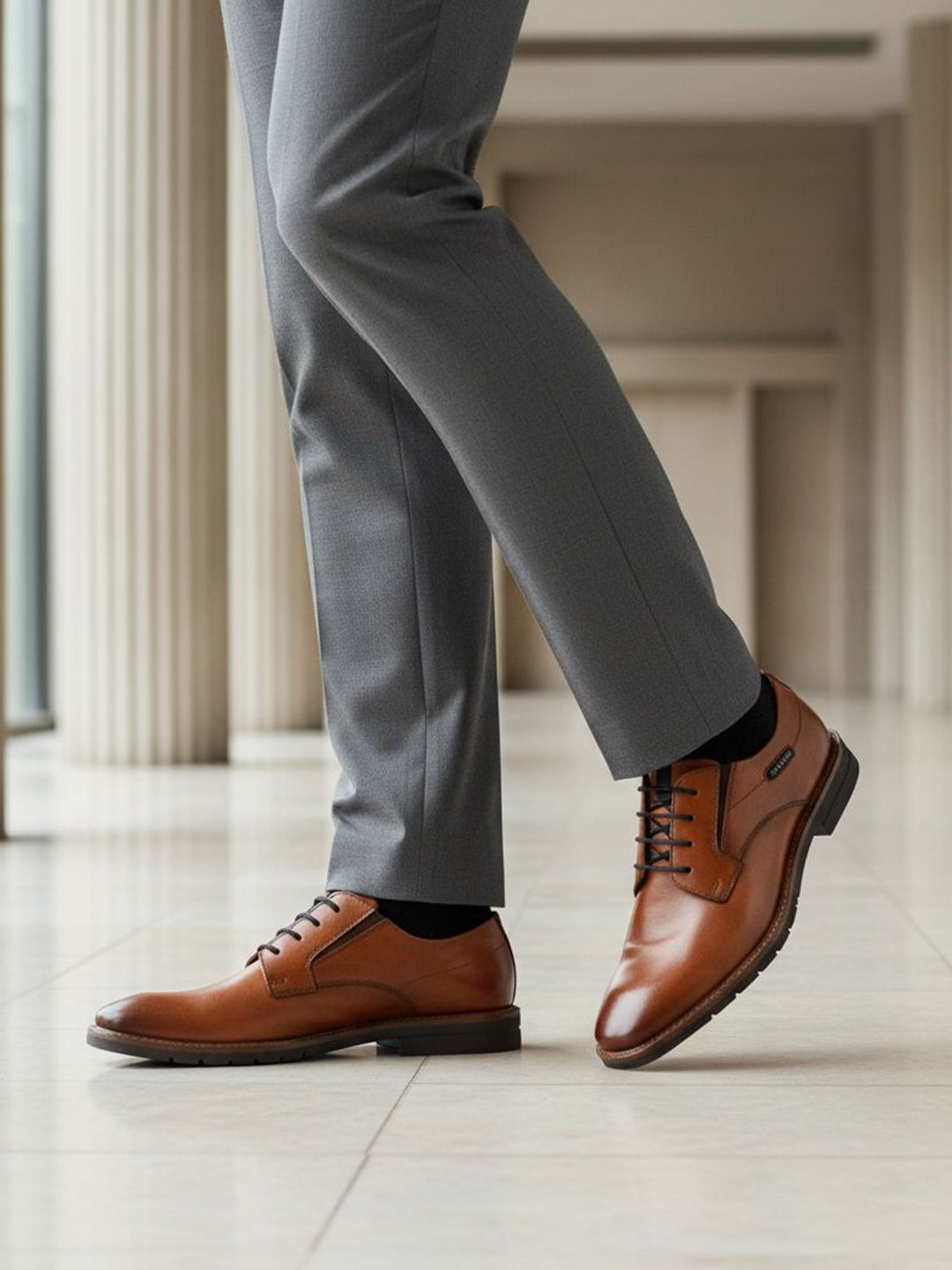 bugatti Mero cognac premium leather derby formal shoes with black laces, styled with gray dress pants and black socks.
