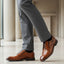 bugatti Mero cognac premium leather derby formal shoes with black laces, styled with gray dress pants and black socks.
