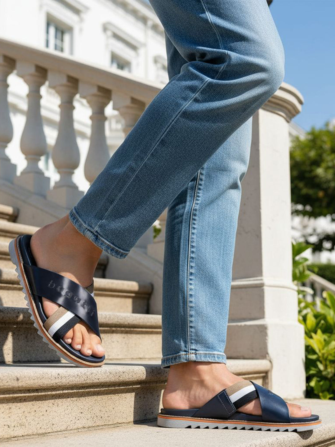 bugatti Limon dark blue leather sandals with cross straps, worn with jeans on stairs.
