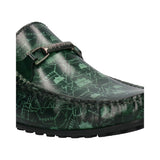 Cropped view of a green leather bugatti loafer with a decorative silver buckle and all-over printed graphic design.
