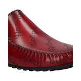 Cropped view of a dark red, leather, casual, bugatti slip-on shoe with the brand name printed on it.
