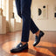 bugatti Mansueto Flex Blue premium leather penny loafers with a silver buckle, worn with navy slacks.