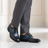 bugatti Livorno Flex Evo dark blue leather derby shoes with black accents, styled with gray dress pants.
