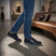 Lifestyle view of bugatti Thorello dark blue leather sneakers with blue jeans and casual indoor setting.
