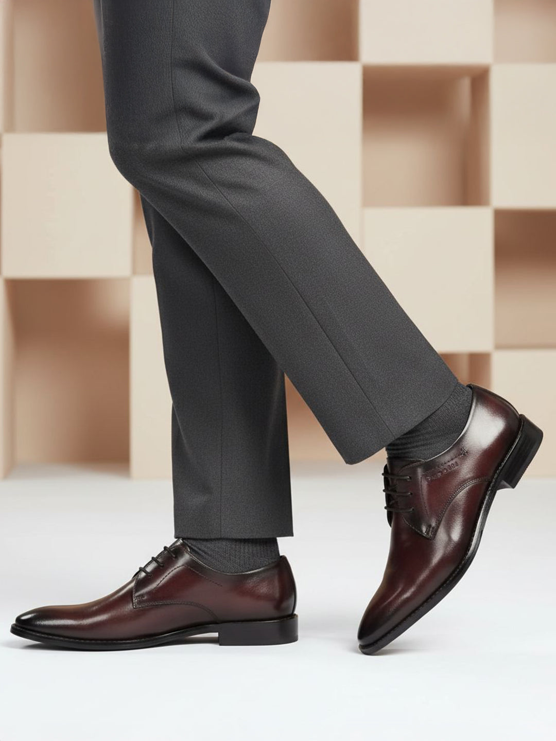 Lifestyle shot of bugatti Rico Flex bordo dress shoes, paired with grey dress pants and grey socks.
