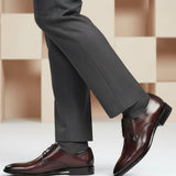Lifestyle shot of bugatti Rico Flex bordo dress shoes, paired with grey dress pants and grey socks.