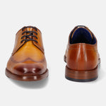 Tan leather dress shoes by bugatti with black laces, visible blue insole, and slight shadow.