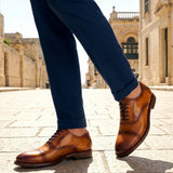 bugatti Liverta yellow leather oxford shoes with dark laces and decorative stitching worn with dark blue pants.
