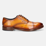 Yellow premium leather oxford shoes by bugatti, featuring brogue detailing and dark brown laces, in a side view.
