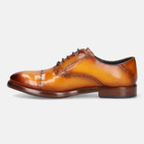 Yellow leather oxford by bugatti, featuring dark laces and decorative brogue detailing, in a side view.
