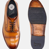 Yellow premium leather Oxford dress shoe by bugatti, showing decorative broguing and black laces, alongside view of the sole.
