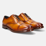 Yellow leather dress shoes by bugatti with black laces, set against a white background.