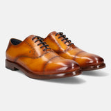 Yellow leather dress shoes by bugatti with black laces, set against a white background.