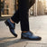 Lifestyle shot of bugatti blue premium leather comfort derby dress shoes worn with dark pants on a city street.
