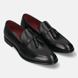 Pair of bugatti Rico black leather slip-on dress shoes with tassels and red lining.
