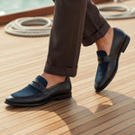 bugatti Rico black premium leather comfort penny loafers with blue accent on a boat deck.