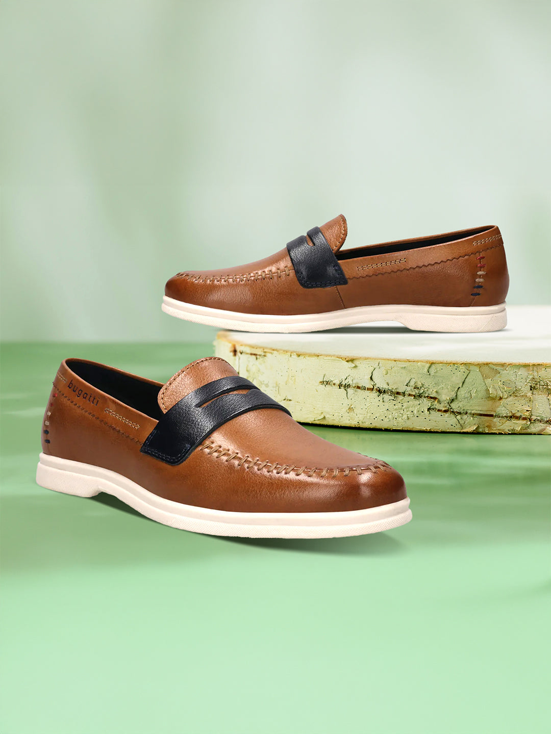 bugatti Sandiago slip-on shoes in cognac leather with a dark accent strap and white soles.
