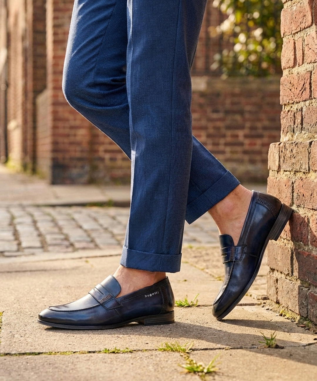 bugatti Matina blue leather penny loafers with a dark finish, worn with blue textured dress pants.
