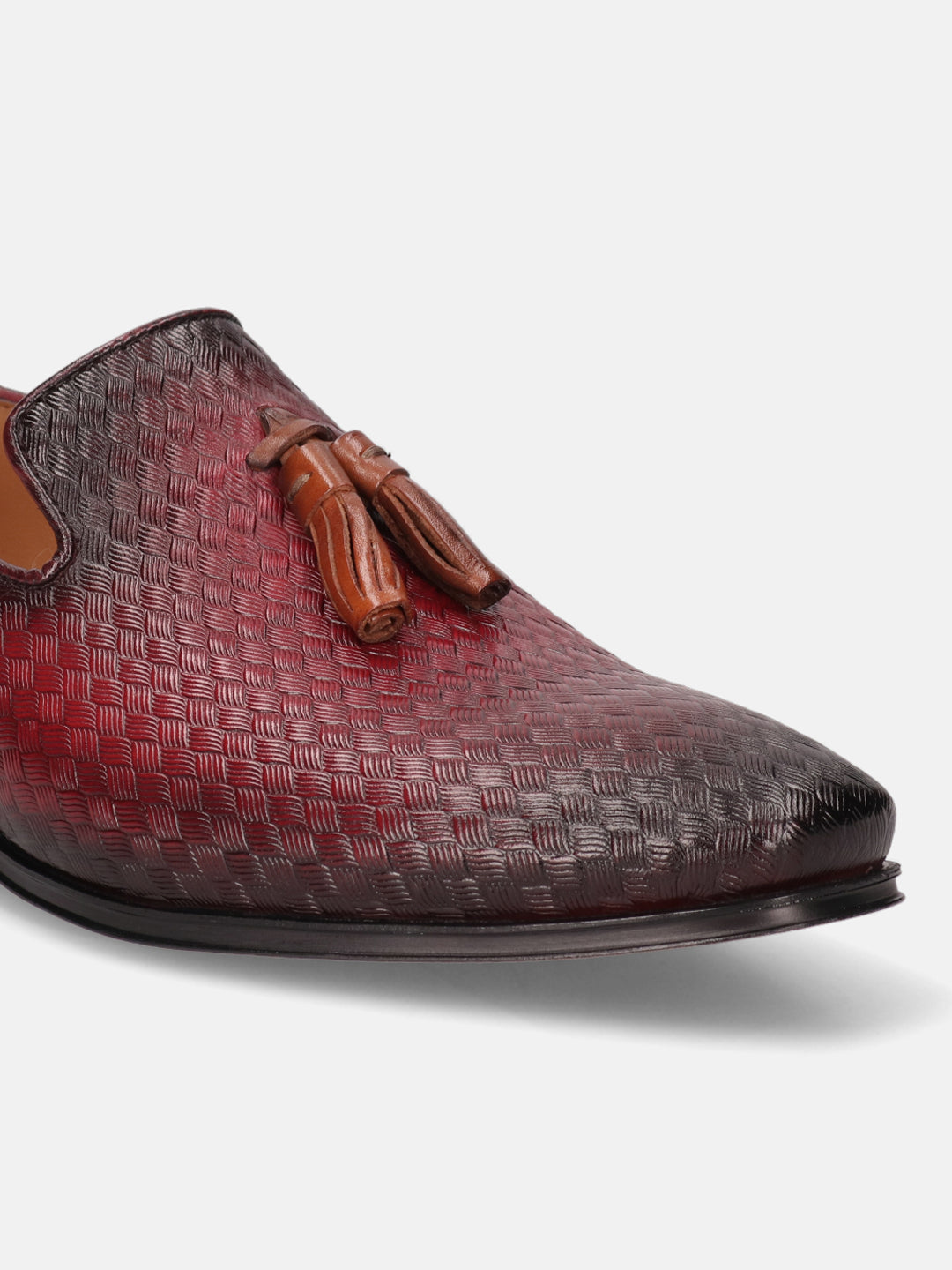 Red leather slip-on shoe by bugatti, with woven texture and decorative tassels.