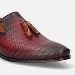 Red leather slip-on shoe by bugatti, with woven texture and decorative tassels.