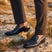 bugatti Margo dark blue premium leather penny loafers worn with gray dress pants on a rocky surface.
