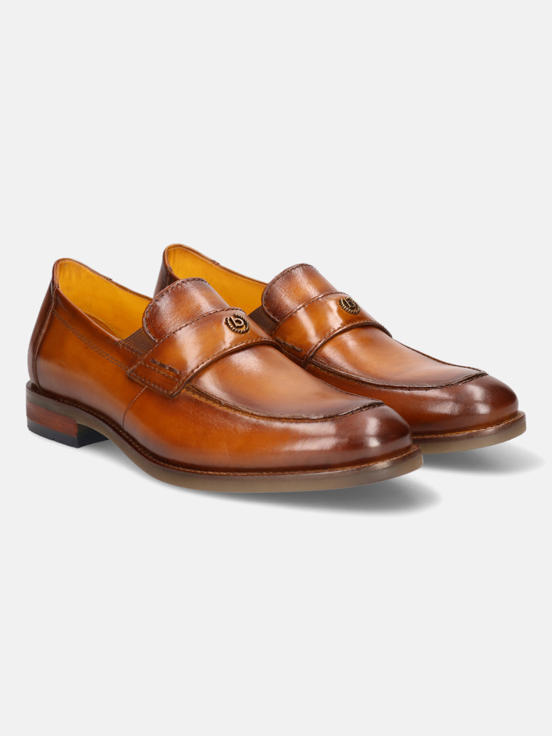 Tan leather penny loafers by bugatti, featuring a golden metal logo on the upper strap and a sleek silhouette.
