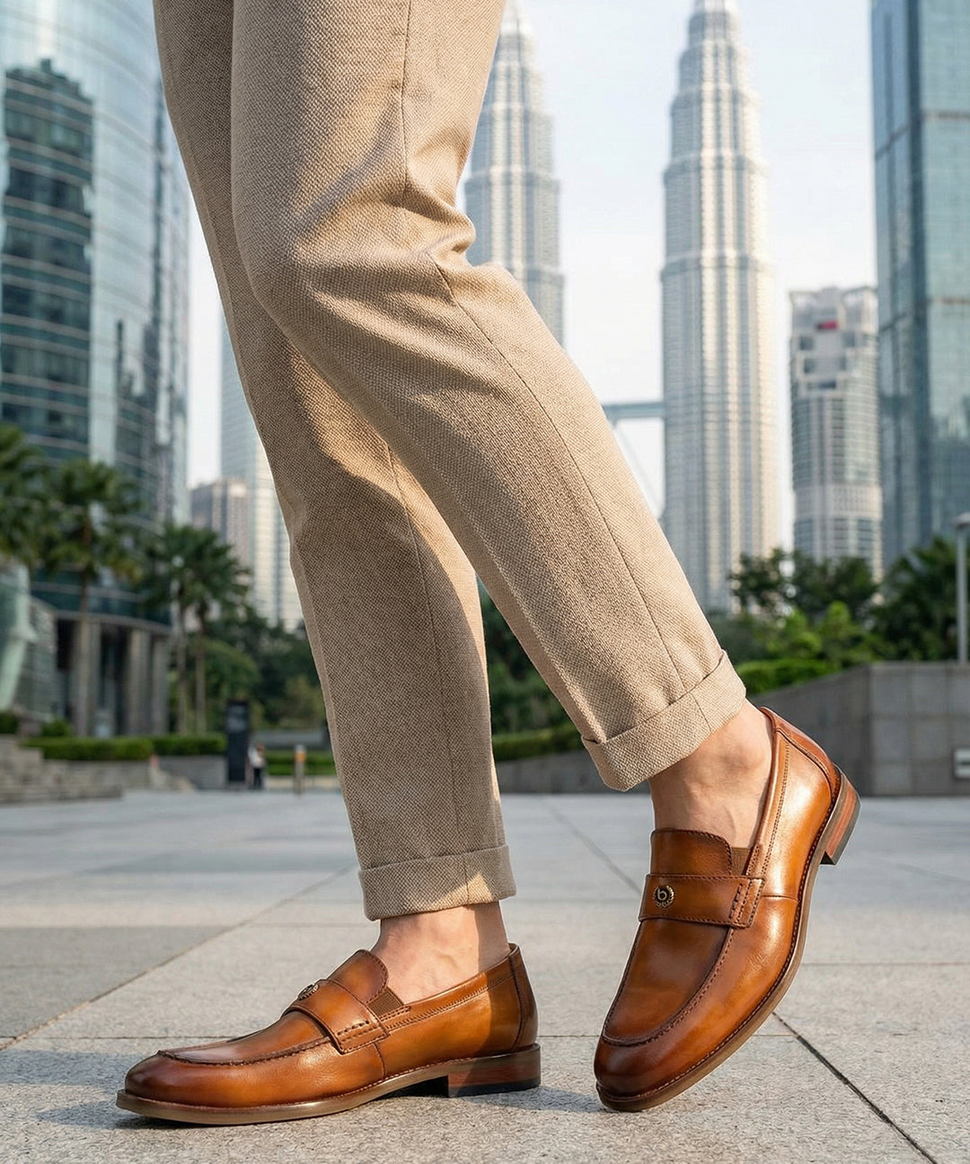 bugatti Sula Revo Yellow premium leather penny loafers, shown with khaki pants on a cityscape background.

