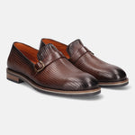 Brown premium leather penny loafers by bugatti, featuring a textured and perforated upper and subtle buckled strap.
