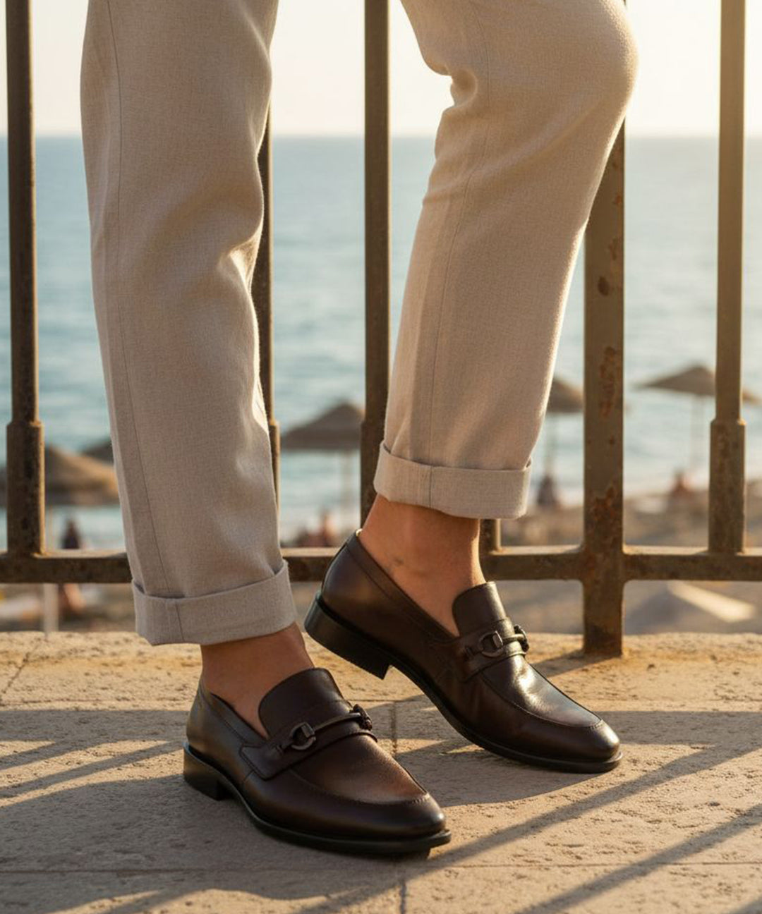Bugatti Mansueto Bordo premium leather comfort slip-ons with a dark brown finish, styled with beige trousers.
