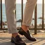 Bugatti Mansueto Bordo premium leather comfort slip-ons with a dark brown finish, styled with beige trousers.

